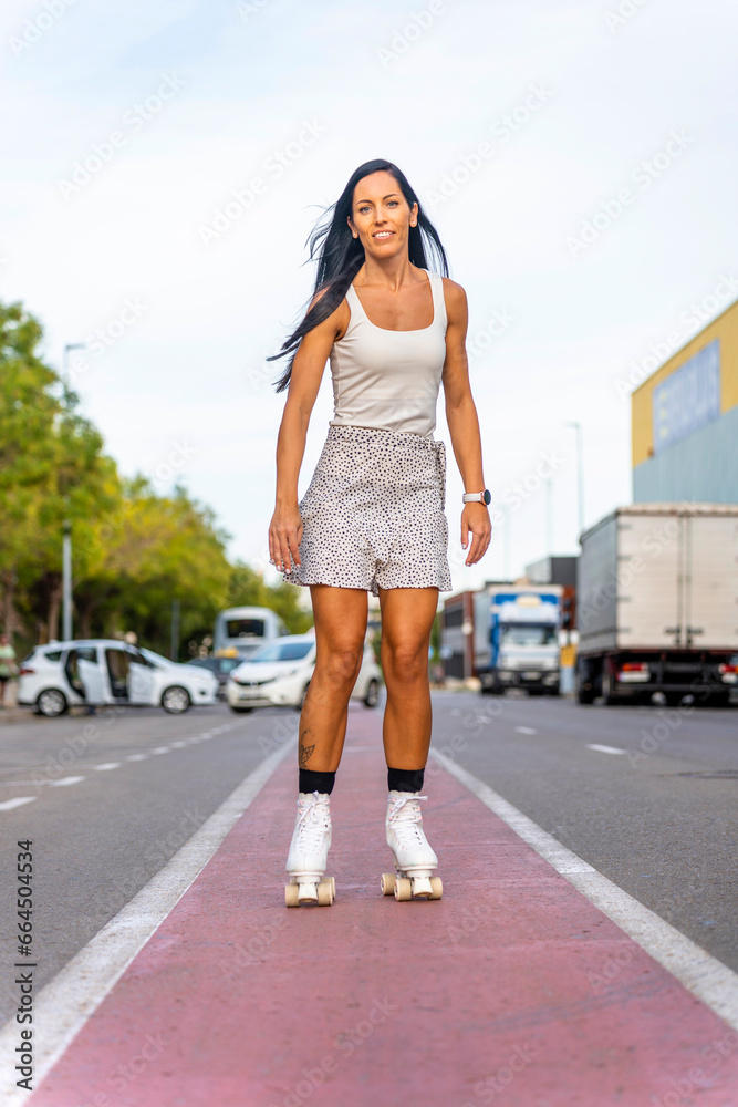 Happy middle aged woman wearing dress smiling while rollerblading asphalt road in sunny day