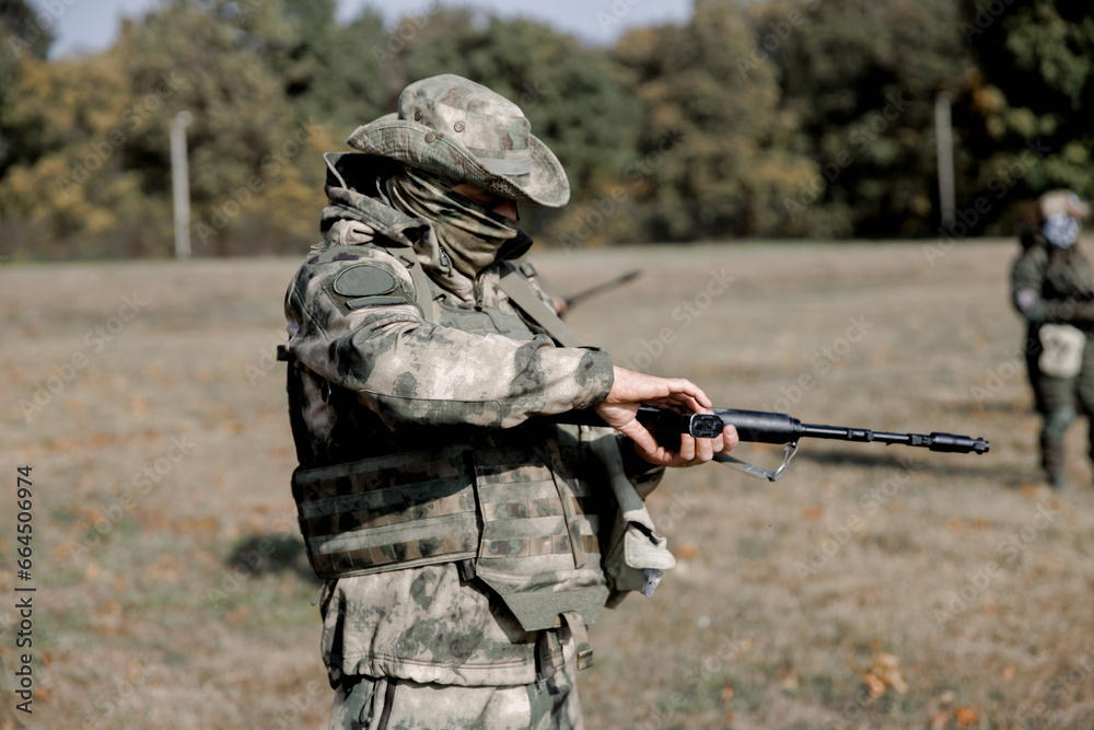 Fototapeta premium Soldiers in formation. Soldiers with a machine gun in military uniform. Special forces with weapons take part in a military maneuver. War, army, equipment and the concept of people. Camouflage. Traini