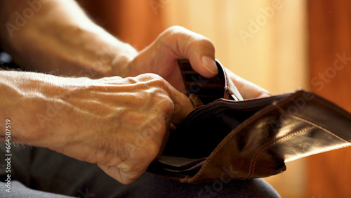 An elderly man's hands, covered with knotted veins, search for coins in his wallet photo