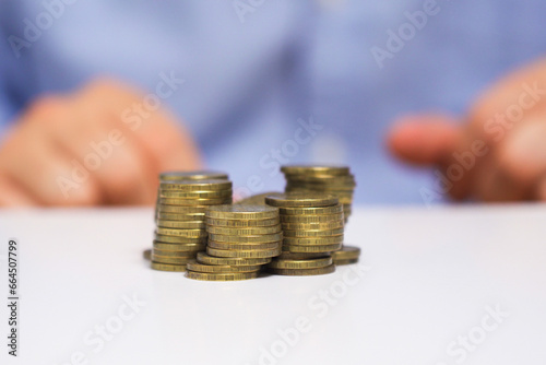 A man's hand moves stacks of coins across the table. Creative concept of stock market movement.