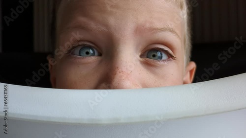 Close up of preschool boy loocking at camera. Blu eyed kid raising eyebrows. photo