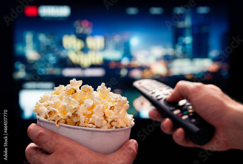 Tv movie night with family. Stream VOD platform. Popcorn and remote control. Video entertainment and snack. Play online film on television. On demand service. Streaming series on digital device. photo