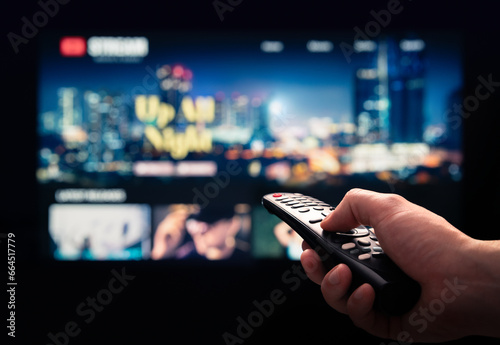 Watching movie stream service on tv. Video on demand subscription service and platform in television. Streaming series, films and shows online. Man using remote control. Person browsing mockup VOD. photo