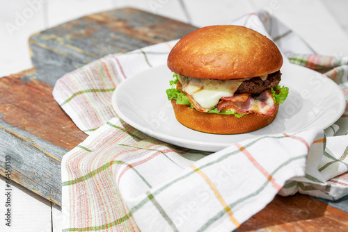 Craft beef burger on plate isolated on wooden background with towel