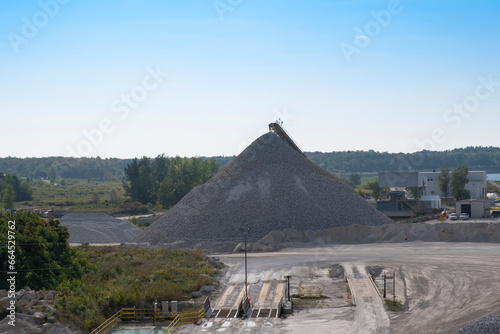 Gravel quarry yard and concrete supply factory with heavy machinery  equipment and piles of processed stones.