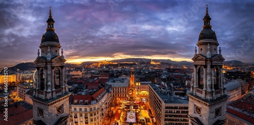 Panoramic view of the skyline of Budapest, Hungary, with a christmas market at the central square during a colorful winter sunset