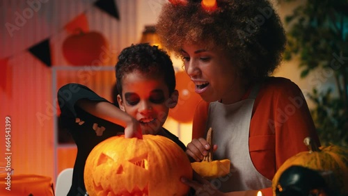 African American kid scaring mom with a toy spider, getting ready for Halloween