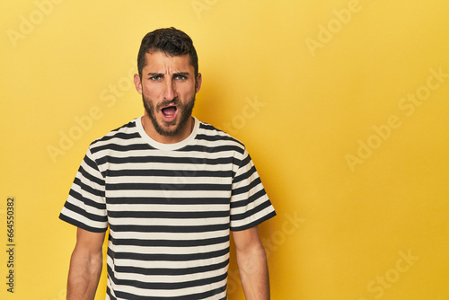 Wallpaper Mural Young Hispanic man on yellow background shouting very angry, rage concept, frustrated. Torontodigital.ca
