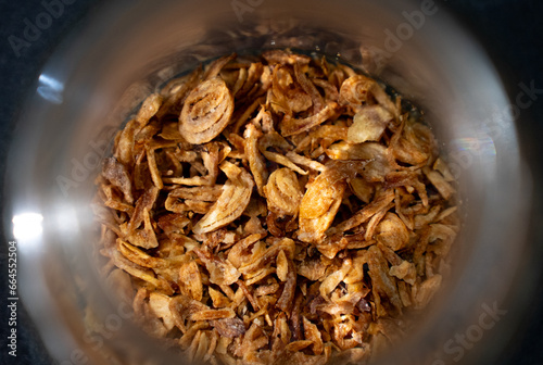 Fried onions (Bawang goreng) in a small glass or bowl. Bawang goreng are sliced ​​red onions that are fried until golden and crispy. Very popular in Indonesia. (close up) (top view)