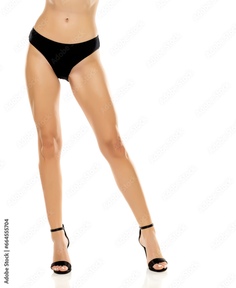 The elegance of women's legs is showcased as she stands confidently in high heels and black panties, exuding a sense of style and sophistication on a white background The elegance of women's legs is showcased as she stands confidently in high heels and black panties, exuding a sense of style and sophistication on a white background