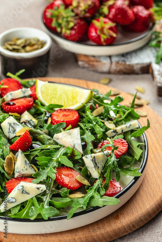 diet summer salad with strawberries, asparagus, arugula, blue cheese and seeds. Food recipe background. Close up