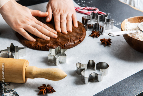 baking, cooking and christmas concept - close up of hands spreading gingerbread dough on black kitchen table top