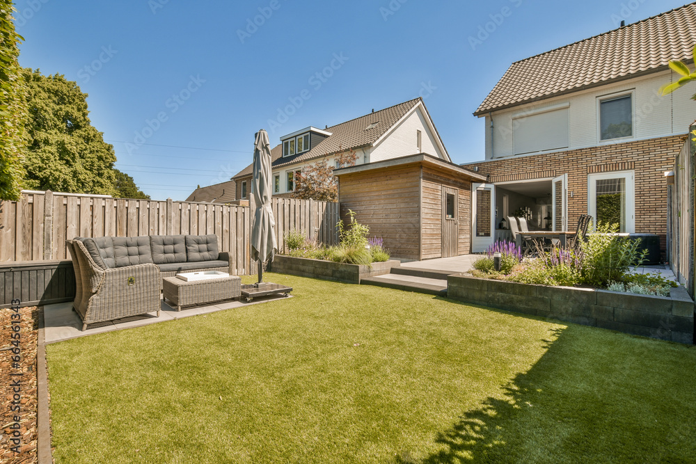 a backyard area with lawn, couch and fenced in the back yard on a clear blue sky day stock photo - obrazy, fototapety, plakaty 