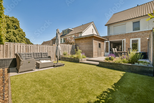 a backyard area with lawn, couch and fenced in the back yard on a clear blue sky day stock photo photo
