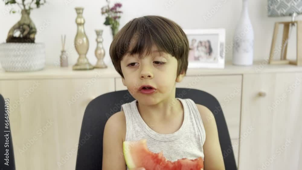 Happy Kid Snacking on Watermelon at the Dining Table during Afternoon Treat Happy Kid Snacking on Watermelon at the Dining Table during Afternoon Treat