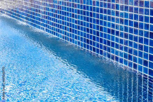 A blue pool with a tiled wall along which water flows. Rest and relaxation
