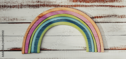 arcobaleno realizzato in legno colorato su una superficie in legno grezzo bianca, vista da sopra photo