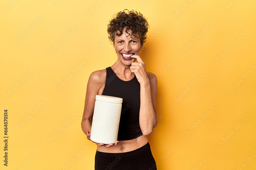 MIddle aged athlete woman holding protein supplement on yellow biting fingernails, nervous and very anxious. MIddle aged athlete woman holding protein supplement on yellow biting fingernails, nervous and very anxious.