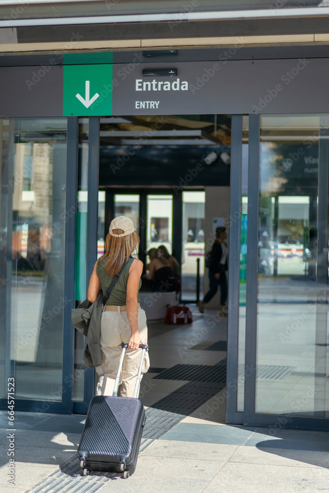 Young woman with luggage entering the railway station. Travel concept