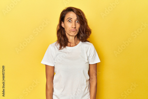 Middle-aged woman on a yellow backdrop sad, serious face, feeling miserable and displeased. photo