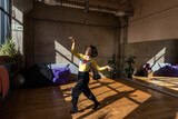 A girl dances a contemporary dance in a sunlit studio