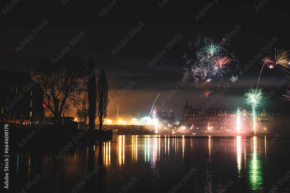 New Year's Eve midnight fireworks over the promenade of Peterhausen and the Rhine bridge, taken from the boardwalk next to peninsula. Constance, Lake Constance, Baden-Württemberg, Germany.