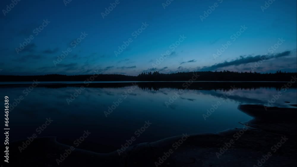 Time lapse of early autumn morning by a lakeshore in the forests in Finland with cloud movement reflected on the water surface Time lapse of early autumn morning by a lakeshore in the forests in Finland with cloud movement reflected on the water surface