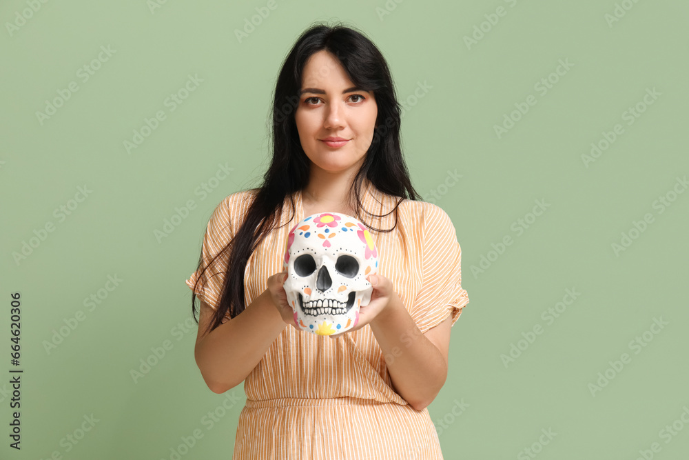 Beautiful young woman with painted skull on green background. Mexico's Day of the Dead