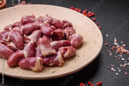 Fresh raw chicken, turkey or duck hearts on a ceramic plate with salt and spices