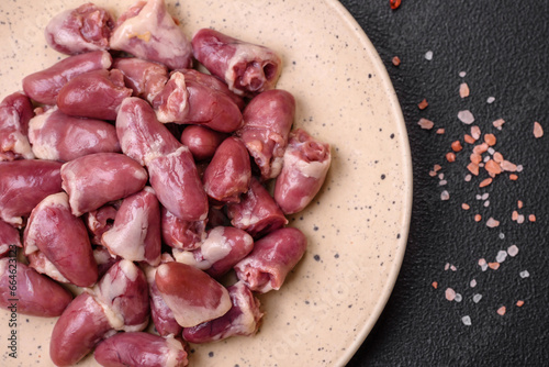 Fresh raw chicken, turkey or duck hearts on a ceramic plate with salt and spices