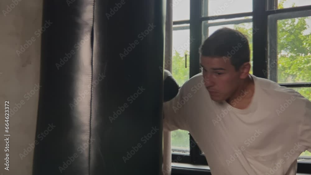 Energetic guy professional sport instructor practicing punches and technique with boxing sports equipment in fitness room. Mid shot
