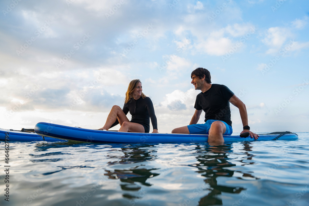Obraz premium Young man and young woman enjoying a day of paddlesurfing