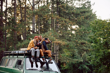 Happy couple of campers taking selfie at trailer park in autumn.