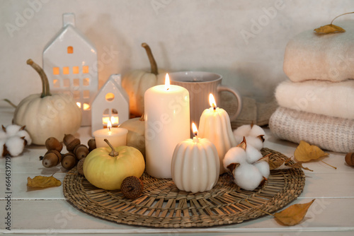 Composition with burning candles and beautiful autumn decor on light wooden table