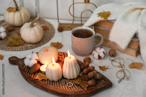 Composition with burning candles  cup of tea and autumn decor on light table