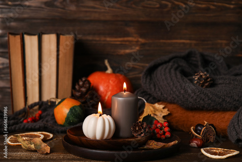 Beautiful autumn composition with candles, pumpkins and books on brown wooden background