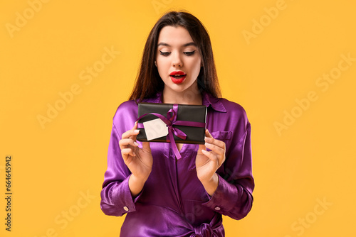 Surprised young woman holdi...