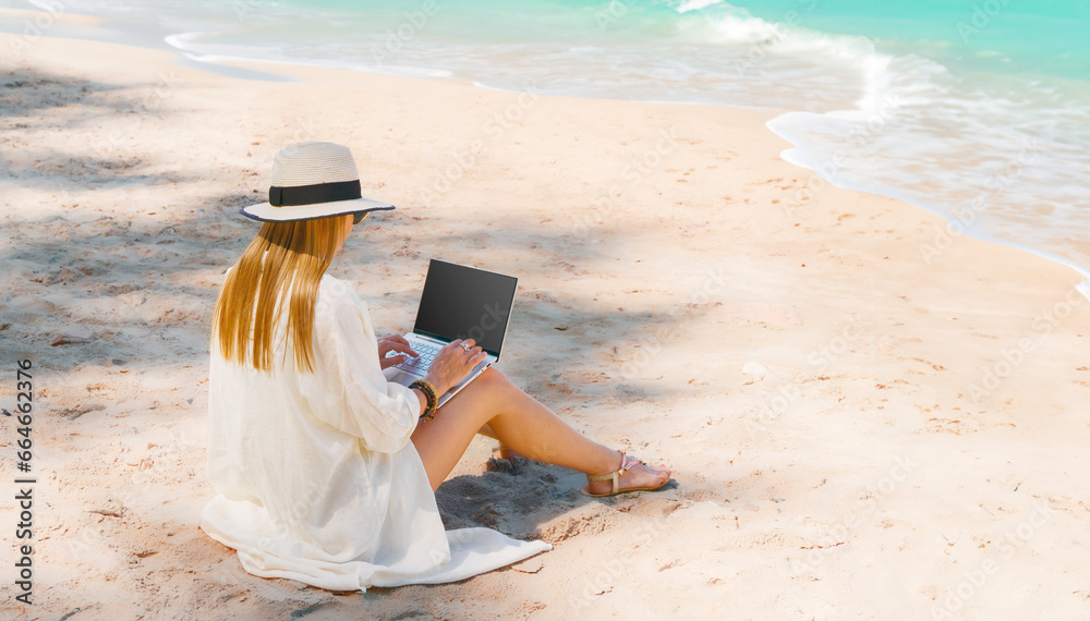 young woman uses laptop computer on the beach. distance work, freelancer and blogger concept. WiFi unlimited