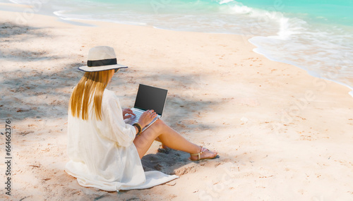 Obraz na płótnie young woman uses laptop computer on the beach. distance work, freelancer and blogger concept. WiFi unlimited w salonie