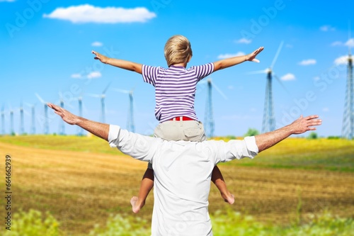 Father holds his child at the wind turbines background