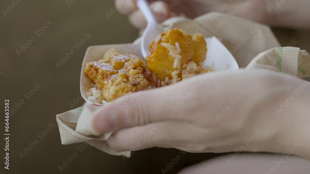 This video shows a plastic fork picking up orange chicken from a concession snack meal. This video shows a plastic fork picking up orange chicken from a concession snack meal.