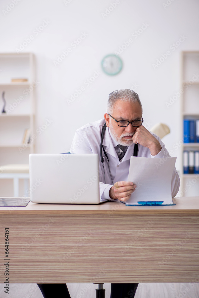 Old male doctor working in the clinic Old male doctor working in the clinic