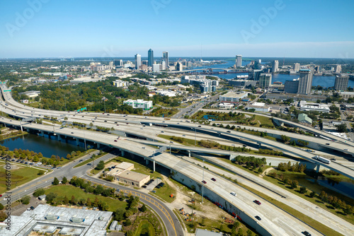 Aerial view of Jacksonville city with high office buildings and american freeway intersection with fast driving cars and trucks. View from above of USA transportation infrastructure