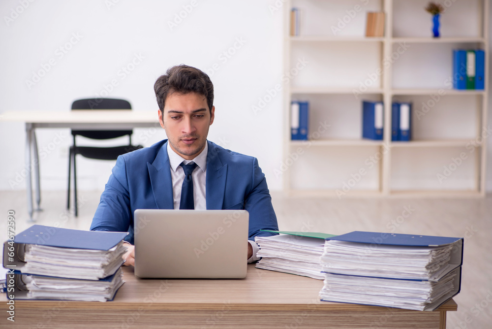 Young male employee and too much work in the office Young male employee and too much work in the office