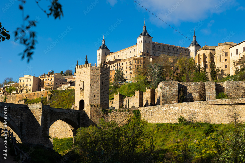 Impressive view of ancient Alcazar of Toledo palace and Alcantara bridge over Tagus river, at capital of province of Toledo in central Spain