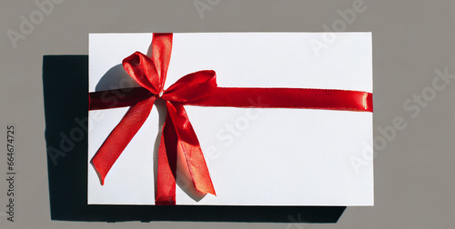 blank minimal white gift card with red rope ribbon bow isolated on grey background with shad