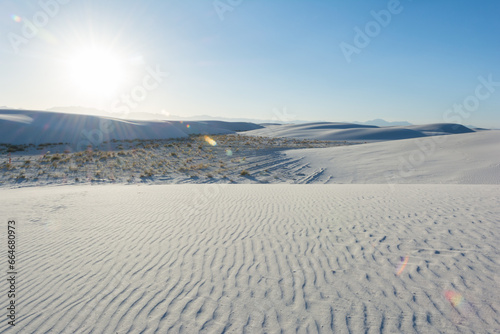 sun setting over white sand dunes