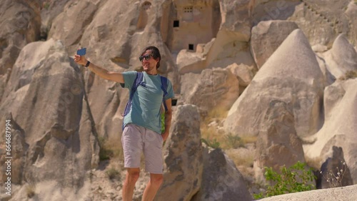 Young man tourist explores the extraordinary rock formations that tell the ancient tales of Cappadocia, Turkey. These surreal rocks, once homes carved by ancient inhabitants, stand as a testament to photo