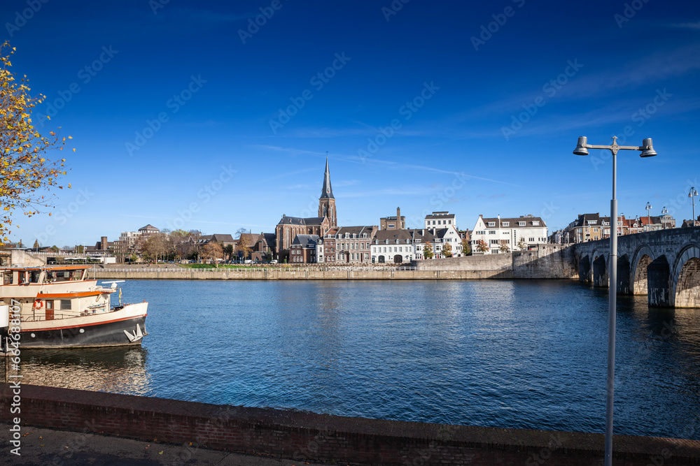Panorama of the Maastricht Waterfront on the Meuse Maas river with a focus on the Sint Martniuskerk, a catholic church, and the saint servatius bridge over the Maas meuse River.
