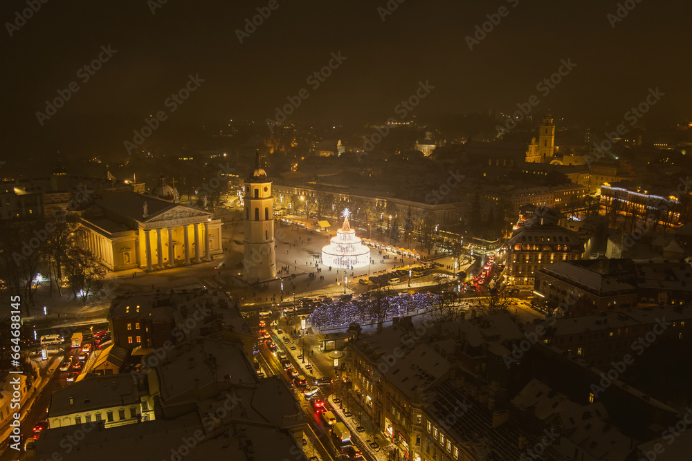 Beautiful aerial view of decorated and illuminated Christmas tree on the Cathedral Square at night in Vilnius. Celebrating Christmas and New Year in Lithuania.